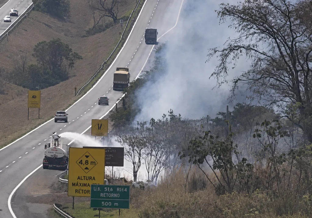 equipes combatem incêndio em margem de rodovia, em foto de plano aberto e distante