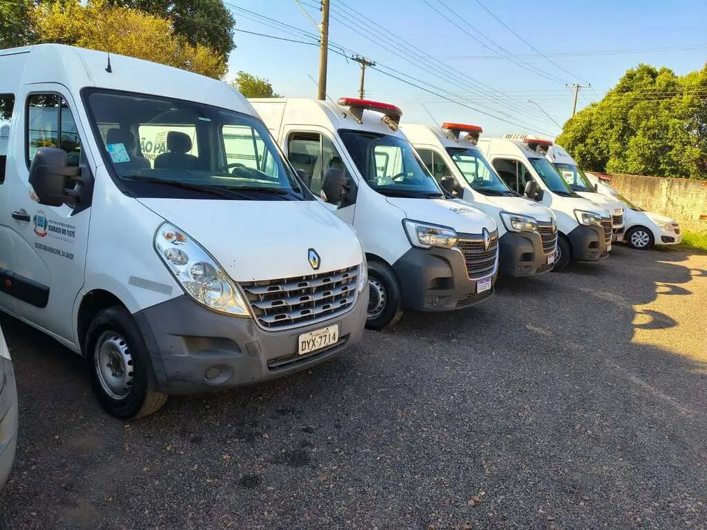 Seis veículos utilizados como ambulância estacionados lado a lado, na cor branca, sendo cinco da espécie furgão
