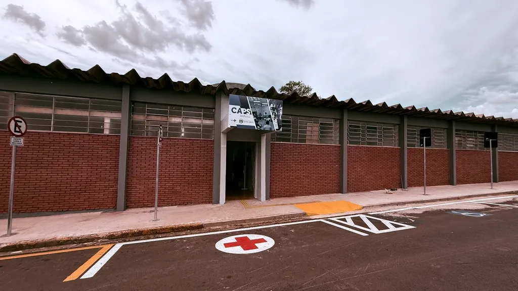 Prédio com paredes de tijolo à vista e janelas superiores, tendo à frente demarcação para estacionamento preferencial