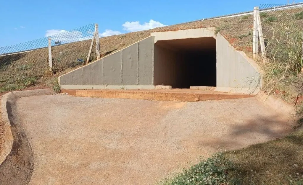 Estrutura de concreto com entrada central, cercada nas laterais com postes e tela alambrado