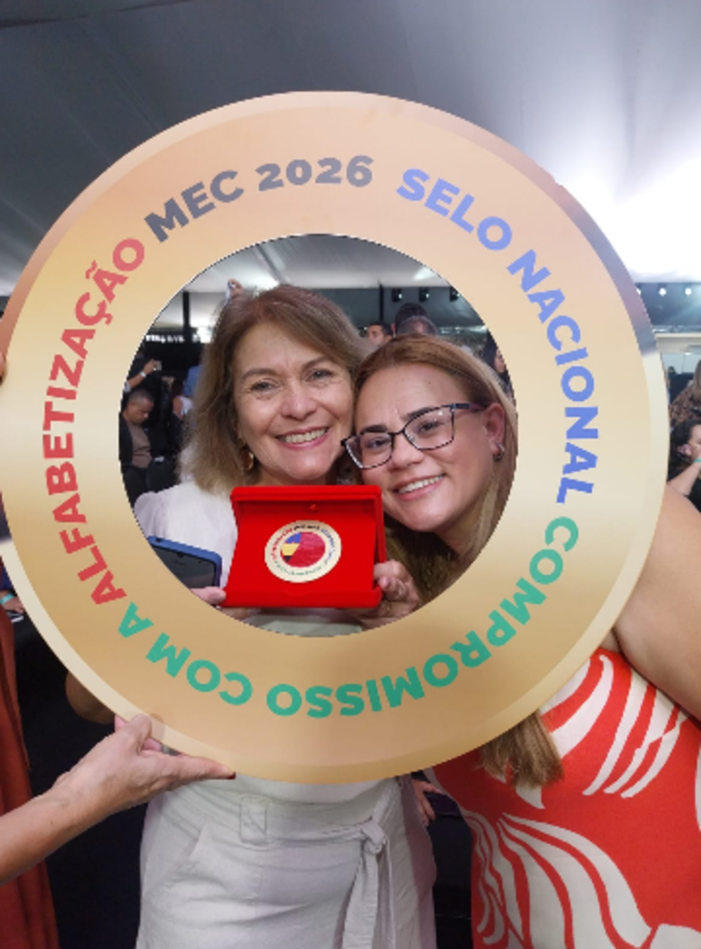 duas mulheres atras de moldura em arco segurando um trofeu