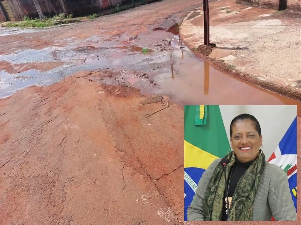 Rua com água parada nas laterais, tendo como destaque uma mulher sorrindo com bandeiras ao fundo