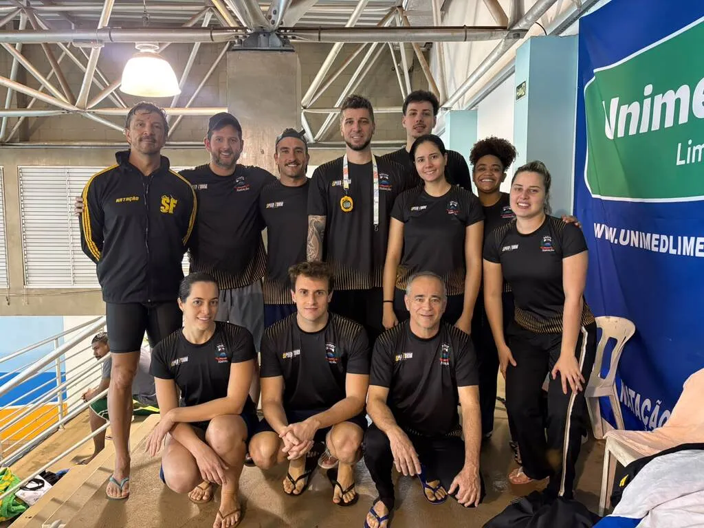 atletas de uniforme preto ao lado de uma piscina